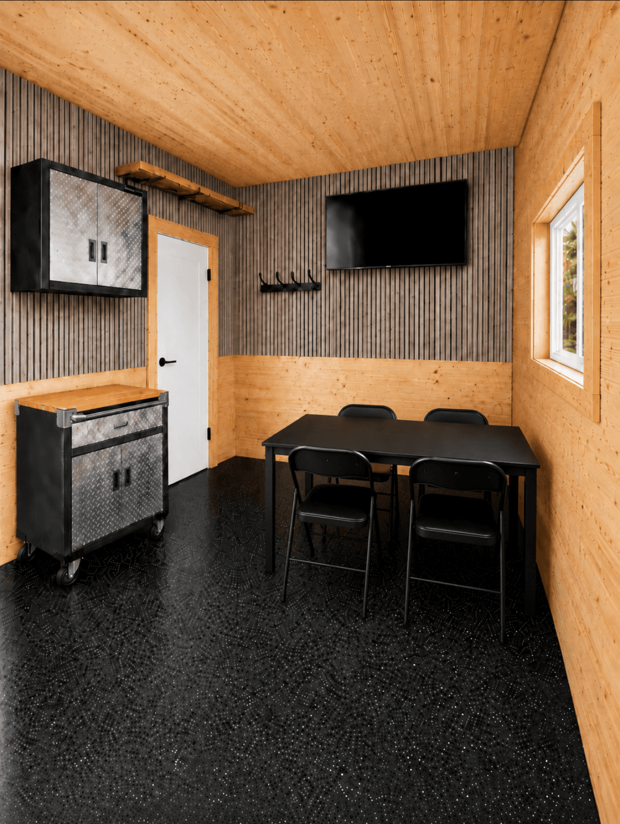 Ice shack interior with light wood ceiling, industrial storage cabinet, dining table and chairs.